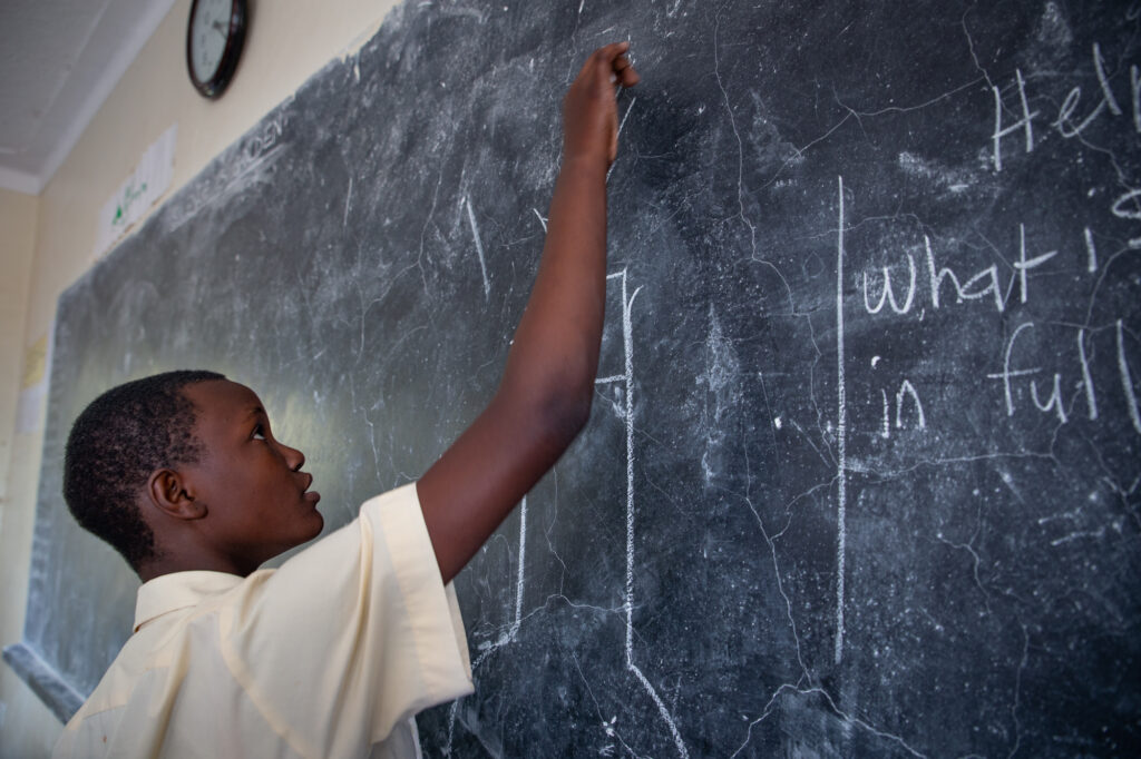 African student writing on board.